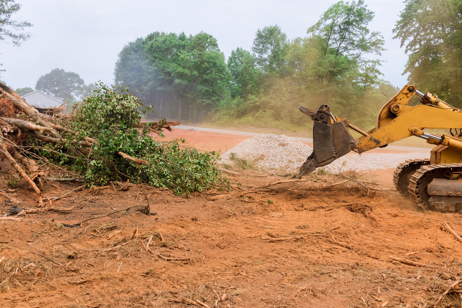 During the uprooting of trees and deforestation, a tractor is working the process to prepare the land for new house construction.